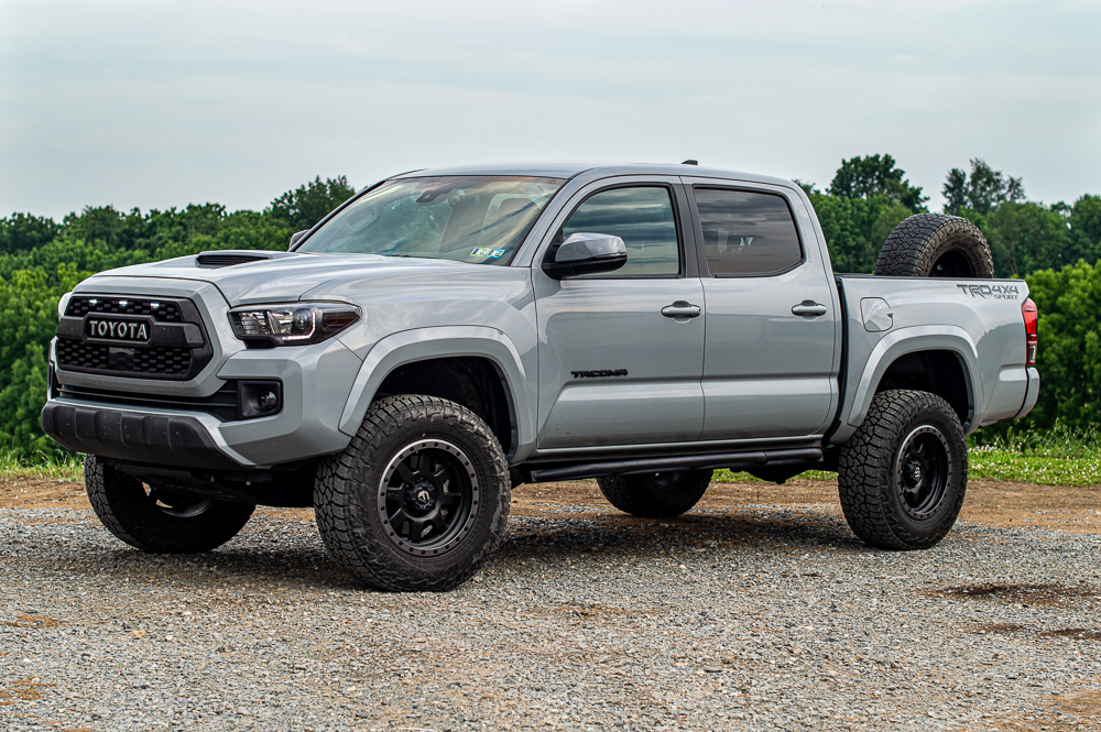 Lifted Cement 3rd Gen Toyota Tacoma with Mobtown Rock Sliders & Truck Bed Mounted Spare Tire Carrier