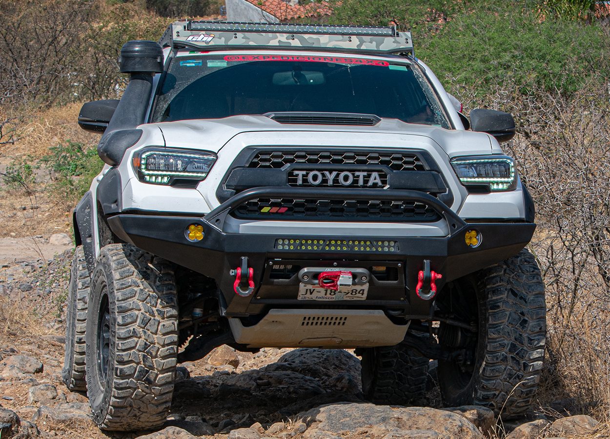 White Tacoma TRD sport with CBI Off-Road steel front bumper with a center grille guard and CBI roof rack