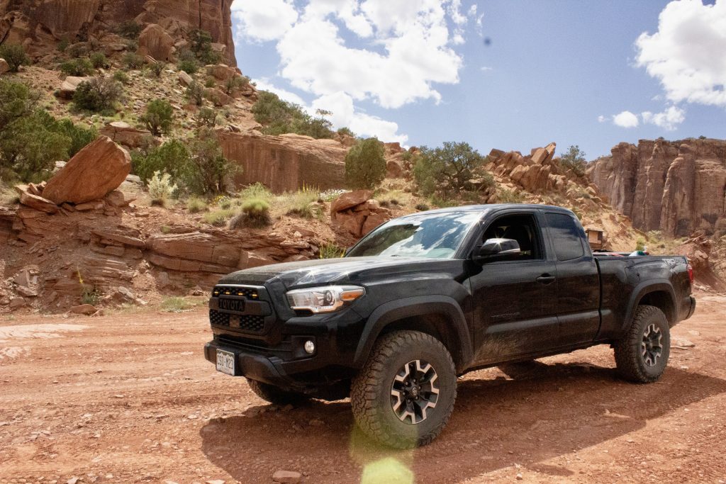 Black stock Toyota Tacoma TRD Off-road on Moab 4x4 trail with Long Canyon in background 