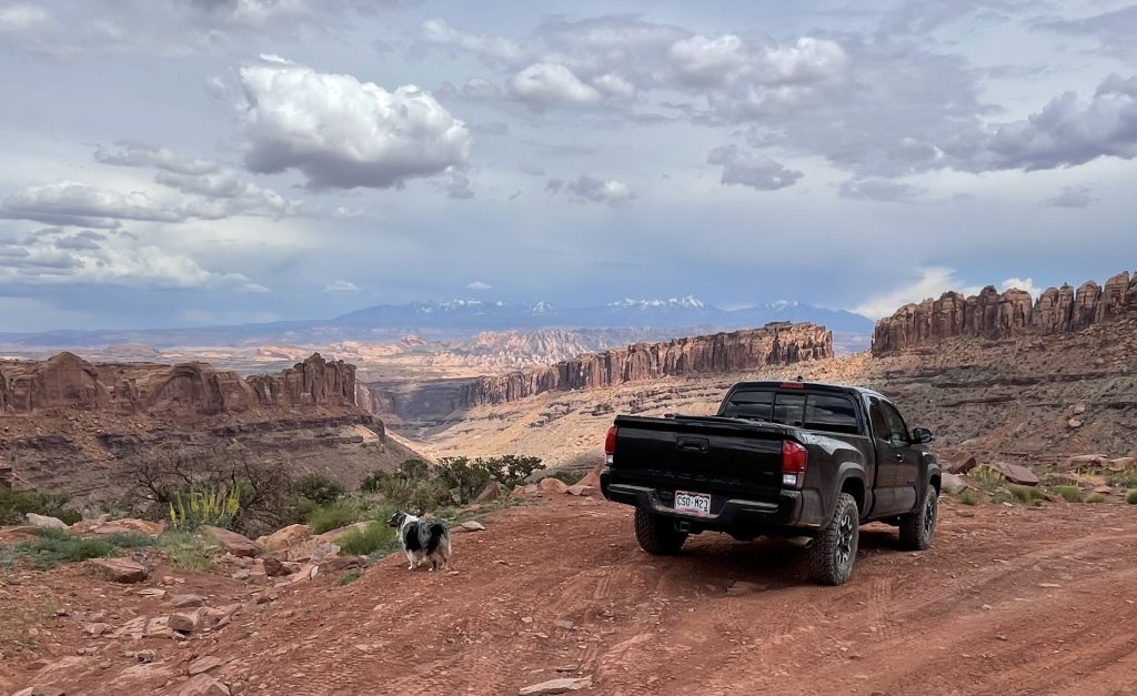 Black Toyota Tacoma overlooking desert and La Sal mountain landscape in Moab, Utah from Long Canyon Road 4x4 trail.