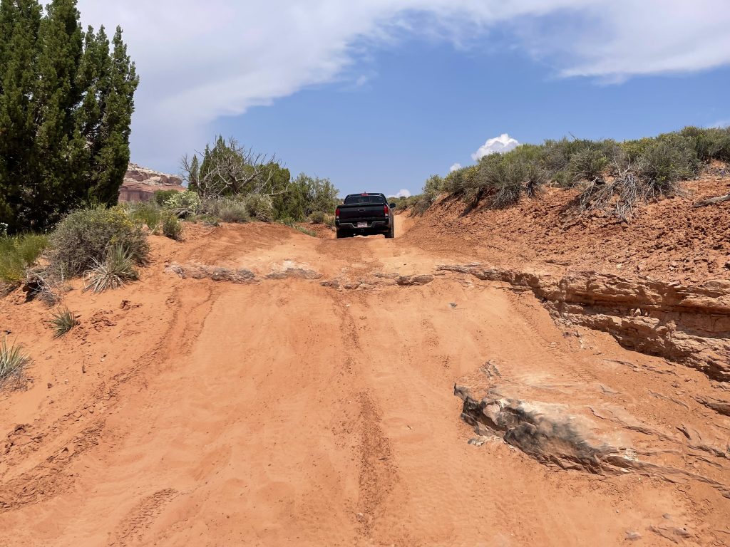 Stock Toyota Tacoma TRD Off-Road tailgate on sandy trail after climbing steep Moab 4x4 obstacle.