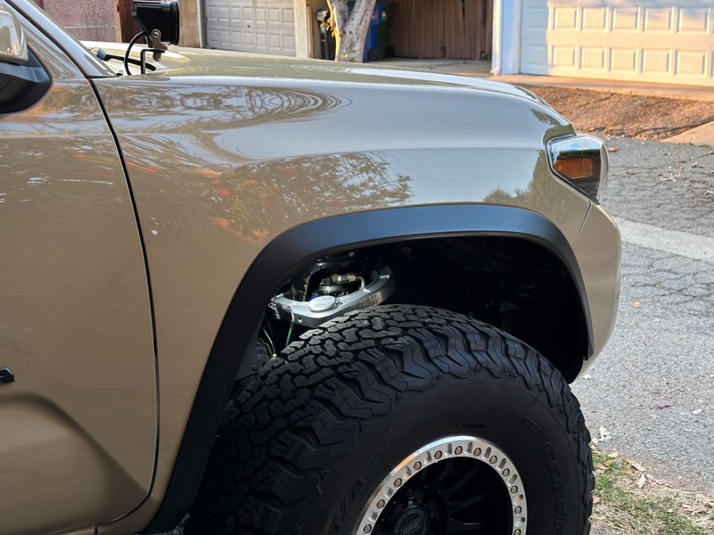 rock light illuminates RRW Billet upper control arm on 3rd gen tacoma parked in driveway